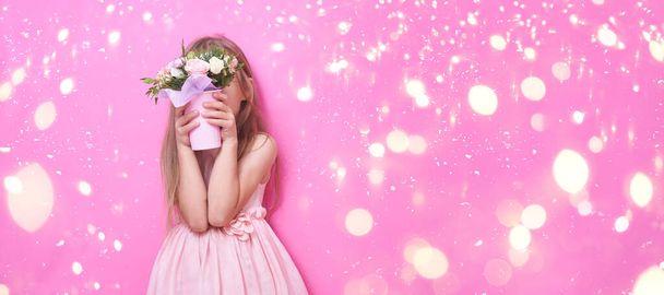 Uma menina em vestido rosa com buquê de flores, escondida atrás das flores. - Foto, Imagem