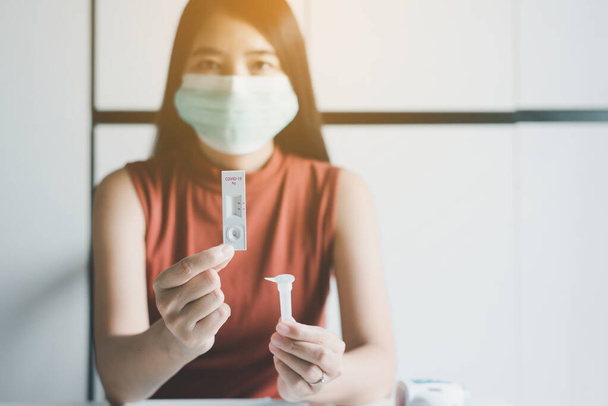 Азійська жінка-пацієнтка, яка використовує коварід-19, швидко тестує антиген вдома. - Фото, зображення