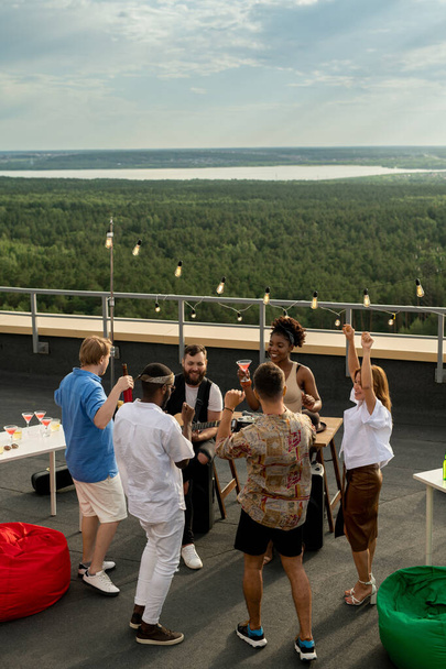 Groep van extatische vrienden dansen op het dak patio - Foto, afbeelding