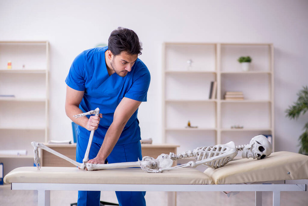 Young male doctor examining skeleton patient - Foto, Imagen