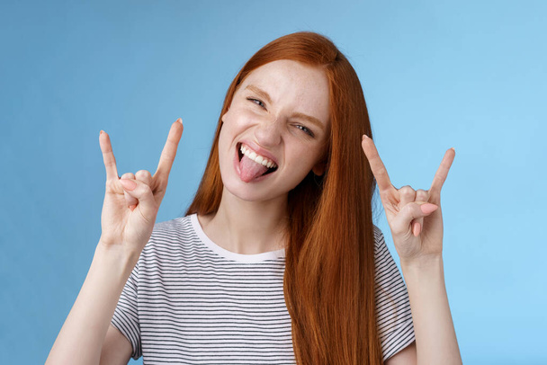 Daring carefree playful excited good-looking funny redhead girl having fun show tongue squinting do thrilled grimace make rock-n-roll heavy metal sign enjoy awesome party cool concert - Foto, Imagen