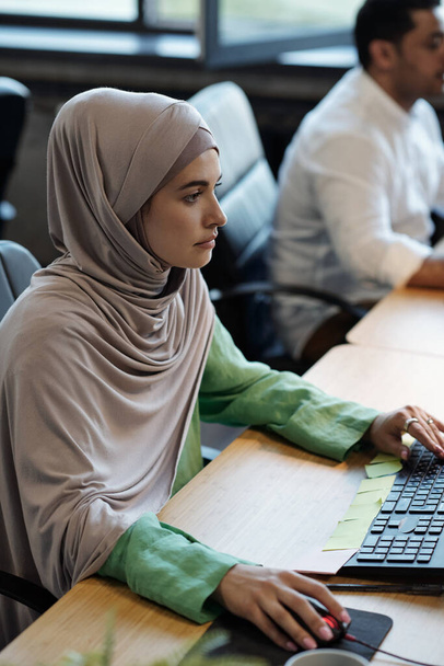 Hübsche muslimische Geschäftsfrau sitzt vor dem Computer - Foto, Bild