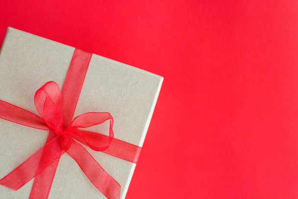 Χριστουγεννιάτικο κουτί δώρου σε κόκκινο φόντο στη γωνία με κενό χώρο για κείμενο. Κάτοψη του παρόντος για το Νέο Έτος, Ημέρα του Αγίου Βαλεντίνου ή άλλες διακοπές - Φωτογραφία, εικόνα