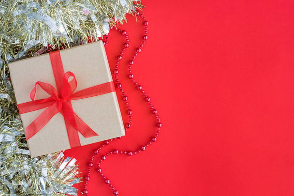 Рождественская композиция на красном фоне с пустым местом для текста. Подарочная коробка с праздничными украшениями - Фото, изображение