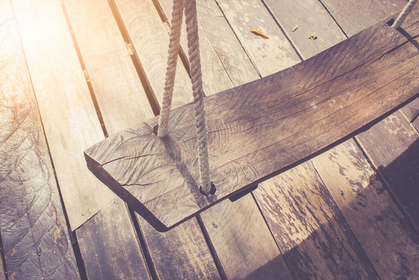 vecchia rustica altalena in legno naturale su pavimento in legno in filtro retrò con luce solare - Foto, immagini