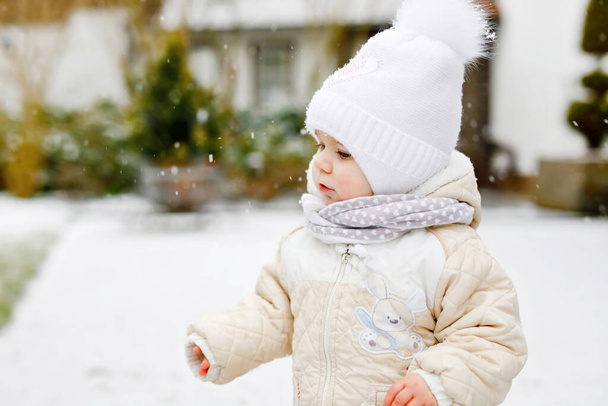 Happy little baby girl making first steps outdoors in winter through snow. Cute toddler learning walking. Child having fun on cold snowy day. Babys first snow, activity. Winter walk outdoors - Photo, Image