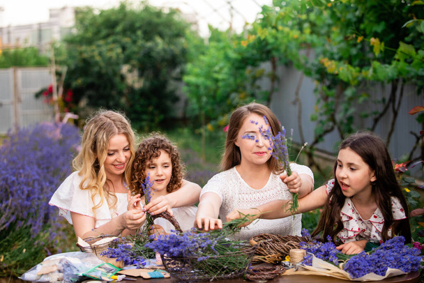 Women with daughters making lavender bouquets outdoors - Fotó, kép