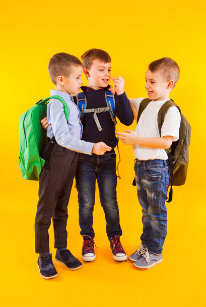 Cute schoolboys in uniform with backpacks on yellow background - Fotoğraf, Görsel
