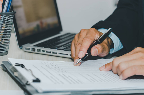 Бізнесмен використовує комп'ютерний ноутбук і паперовий документ для ручки стола. Бізнес-фінанси, податки та інвестиційні концепції
. - Фото, зображення