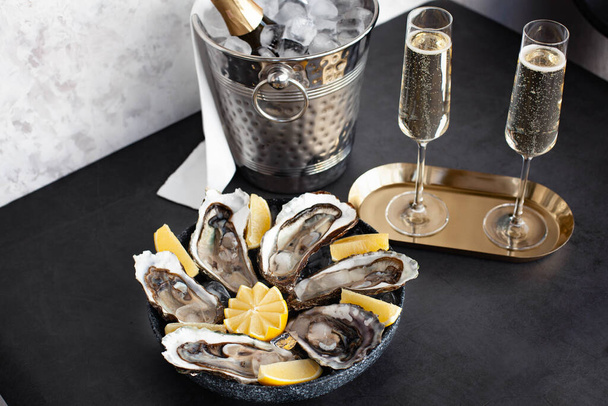 Champagne glasses with sparkling wine and bottle in bucket near oysters - Fotografie, Obrázek