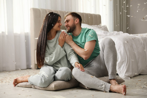 Happy young couple resting after fun pillow fight in bedroom - Fotoğraf, Görsel