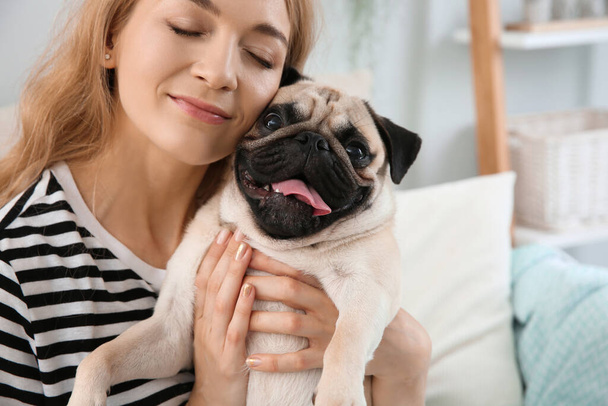 Woman with cute pug dog at home. Animal adoption - Foto, imagen