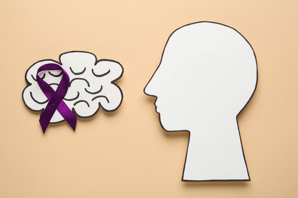 Human head and brain cutouts with purple ribbon on yellow background, flat lay. Epilepsy awareness - Foto, imagen