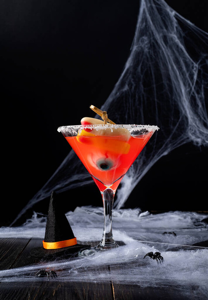 Happy Halloween concept. Scary colorful Halloween cocktail with party decorations on dark background with spider web with copy space - Фото, изображение
