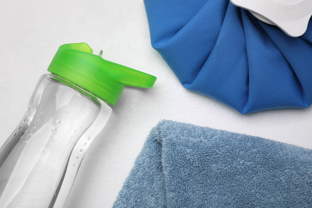 Botella de agua, compresa fría y toalla sobre fondo blanco, plano. Tratamiento de golpe de calor - Foto, Imagen