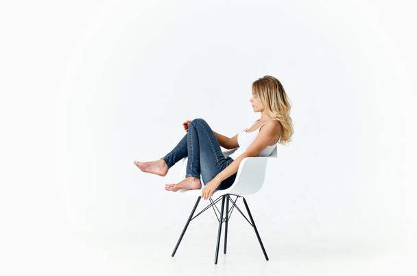 woman jeans sitting on white chair bent legs fashion lifestyle - Fotoğraf, Görsel