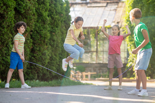 Joyful girl jumping rope with friends - Zdjęcie, obraz