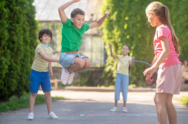 Jumping boy and friends with skipping rope - Foto, imagen