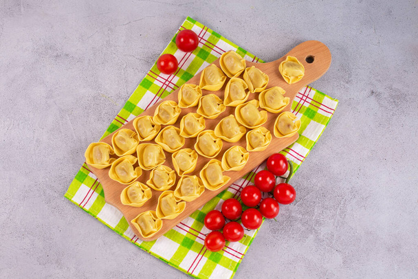 ongekookte tortelloni met champignonvulling op een houten plank. - Foto, afbeelding
