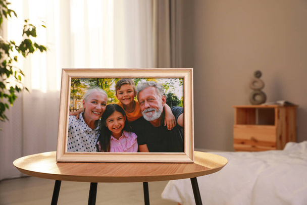 Framed family photo on wooden table in bedroom - Фото, изображение