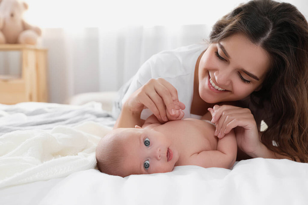 Jovem mãe feliz com seu bebê bonito na cama em casa - Foto, Imagem