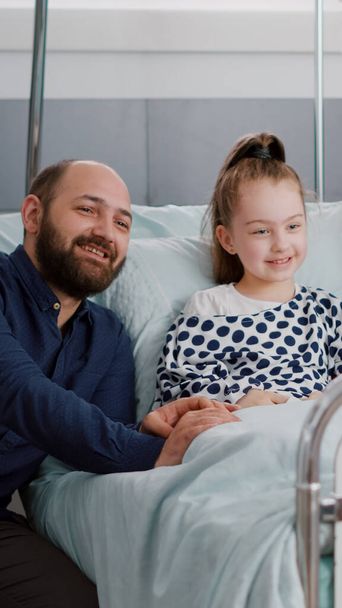Família assistindo filme de desenhos animados na televisão na enfermaria do hospital, enquanto espera por experiência médica doença - Foto, Imagem
