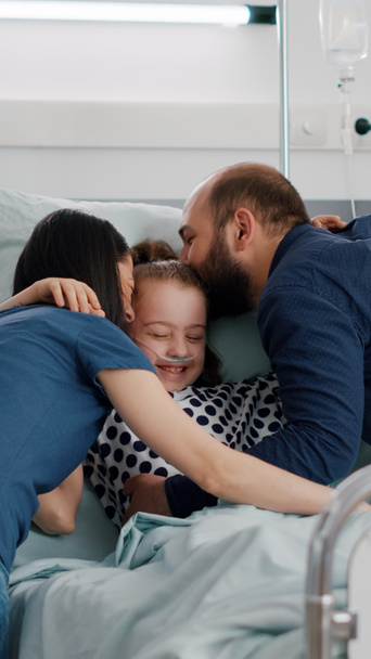Padres felices visitando a la hija enferma abrazando al niño durante el examen de la enfermedad - Foto, imagen