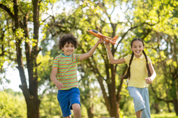 Girl and boy with toy airplane running in park - Photo, Image