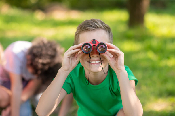 Boy looking through binoculars in nature - Foto, afbeelding