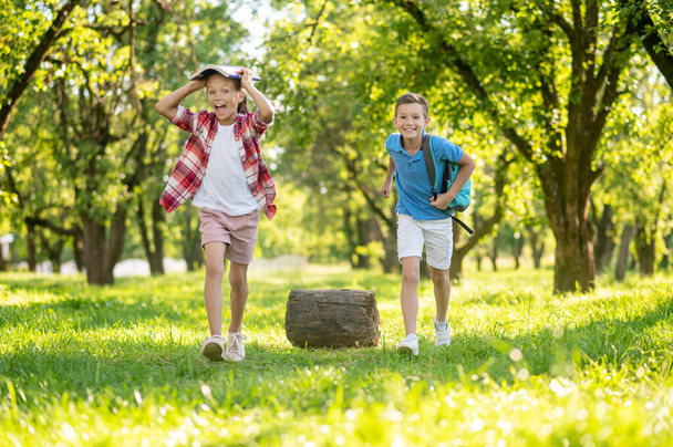 Cheerful girl and boy with backpack in park - Foto, immagini