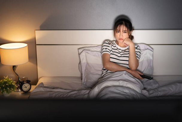 bored young woman watching TV on a bed at night - Valokuva, kuva