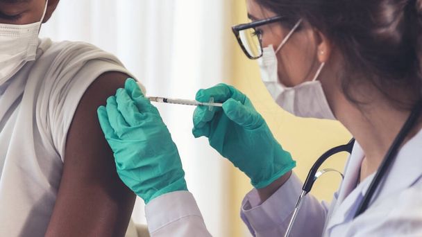 Young man visits skillful doctor at hospital for vaccination - Fotó, kép
