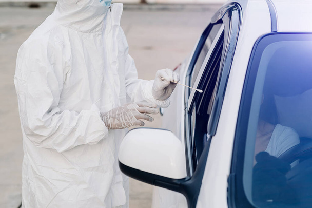 Medical worker in protective suit screening woman Driver to Sampling secretion to check for Covid-19. check,taking nasal swab specimen sample from male patient through car window,PCR diagnostic for Coronavirus  - Fotoğraf, Görsel