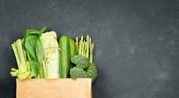 πράσινα λαχανικά σε χάρτινη σακούλα σε σκούρο μπετόν φόντο - Φωτογραφία, εικόνα