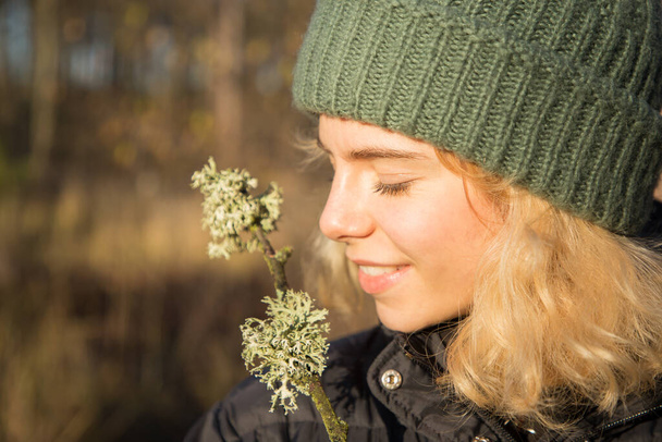 профиль портрет красивой улыбающейся девочки-подростка 17 лет в вязаной зеленой шляпе. Солнечный день, прогулки по лесу, наслаждаясь моментом, цифровой детоксикации - Фото, изображение