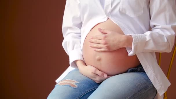 Felice giovane donna incinta in camicia bianca toccare la pancia - Filmati, video