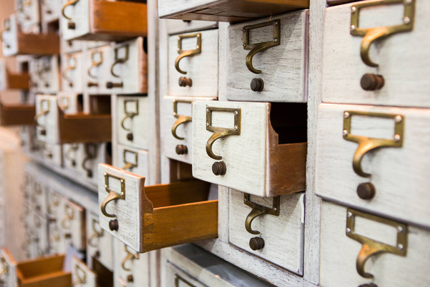 Rows of little drawers with white empty tags in an old furniture module - 写真・画像