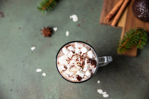 Hot chocolate with marshmallow and cocoa or chocolate bomb. Winter composition with fir branches and spices. Selective focus. Top view. - Foto, afbeelding