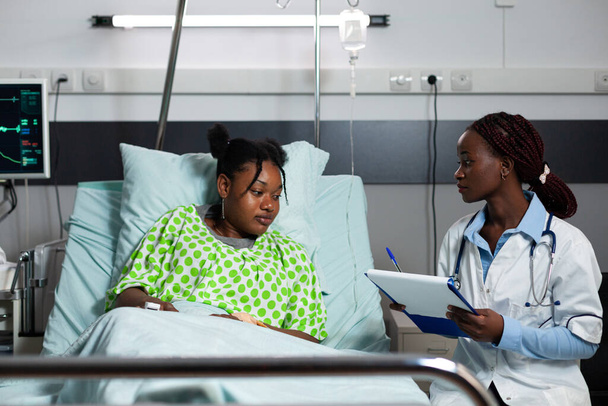 Afrikkalainen amerikkalainen lääkäri ja potilas puhuu sairaalaosastolla - Valokuva, kuva