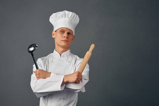 Cheerful chef in uniform kitchen items in the hands of a professional restaurant - Foto, Imagem