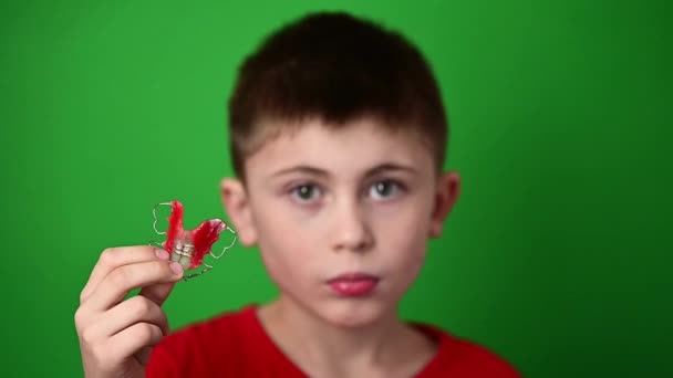 Un niño de 9 años sostiene una placa de alineación dental, una abominación y una demostración de una placa de alineación dental. - Imágenes, Vídeo