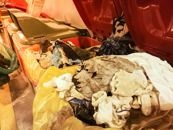 Używana szmata i rękawiczka bawełniana zanieczyszczona olejem posortowanym w czerwonym koszu na śmieci w fabryce, Pełnoczerwony pojemnik na śmieci - Zdjęcie, obraz