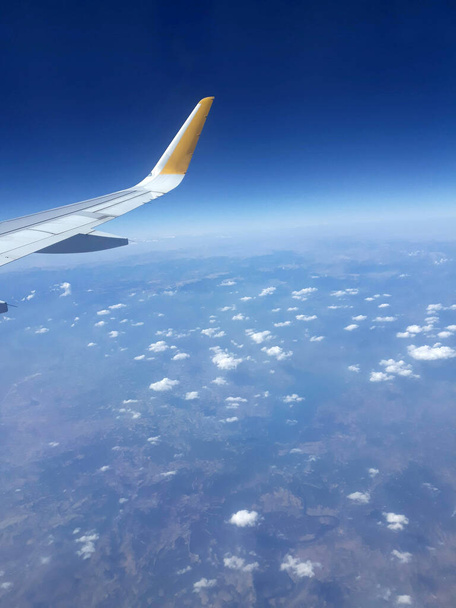 Les fenêtres de l'avion donnent sur la terre. Vue depuis une fenêtre d'avion au-dessus d'une aile volant au-dessus des nuages. - Photo, image