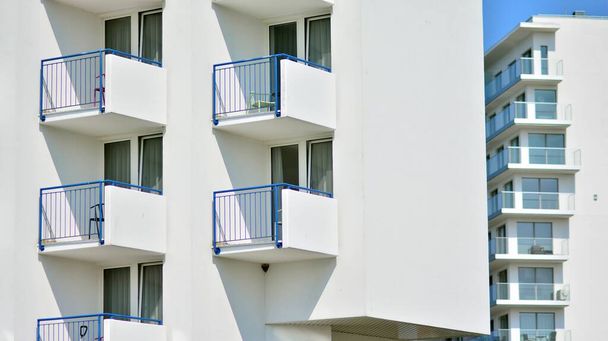 大きな窓のある住宅ビルの近代的な白いファサード。現代的なデザインのコンクリートのアパートの建物の眺め. - 写真・画像