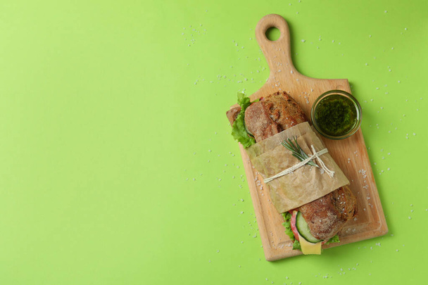 Deska s ciabatta sendvič, omáčka a sůl na zeleném pozadí - Fotografie, Obrázek