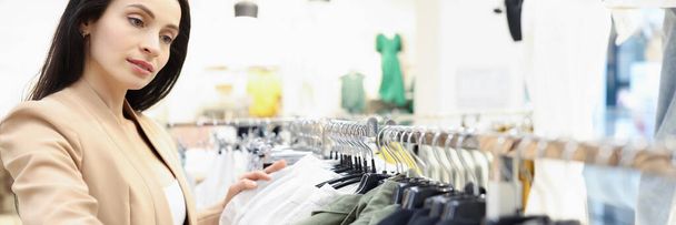Zakelijke vrouw kiest pak in kledingwinkel - Foto, afbeelding