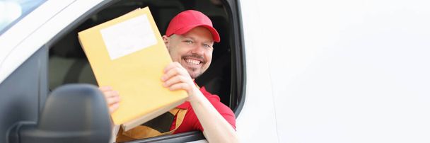 Un conductor de mensajería sonriente sostiene el correo en sus manos - Foto, imagen