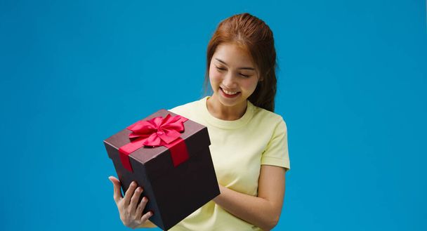 Joven chica de Asia sonrisa y sosteniendo abierto presente caja aislada sobre fondo azul. Copia espacio para colocar un texto, mensaje para publicidad. Área de publicidad, maqueta de contenido promocional. - Foto, Imagen