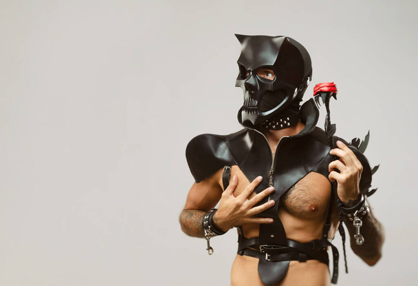 BDsm iblis kafatası maskeli bir adam deri bir pelerin giymiş ve vücudunda deri bilezikler ve kayışlar var. - Fotoğraf, Görsel