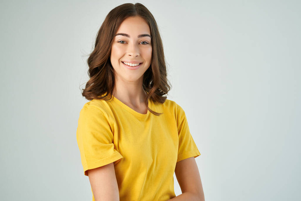 mosolygós nő sárga pólóban divatos frizura pózol közelről - Fotó, kép